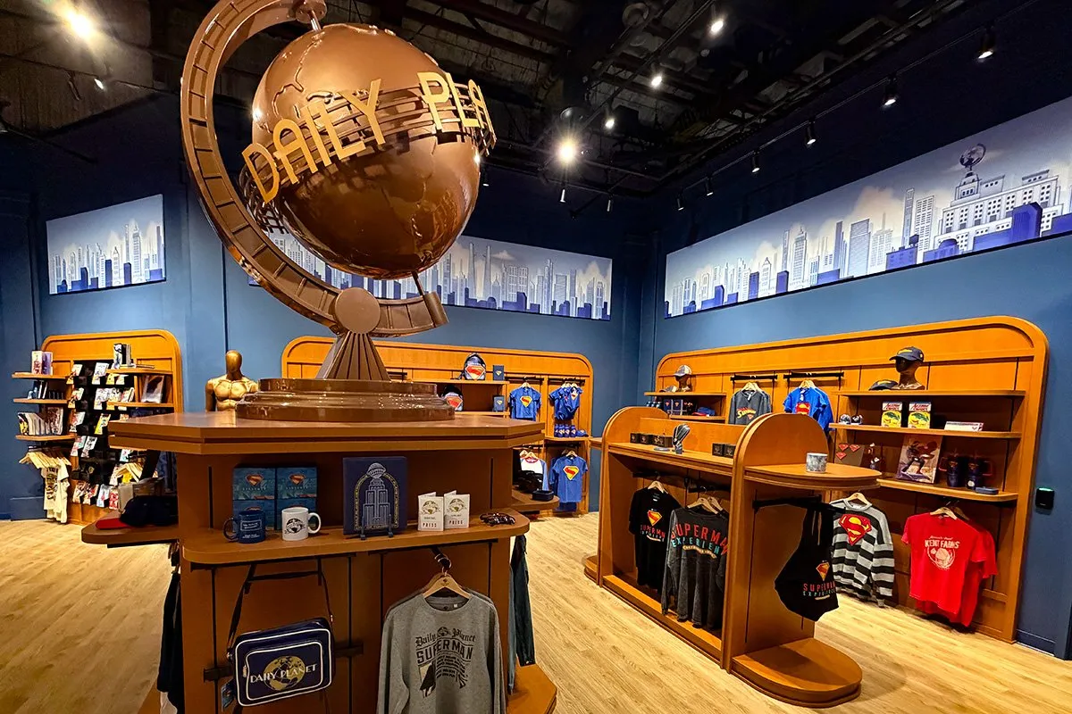 Superman Experience store with items on shelves and a large Daily Planet globe circling as a focal point.